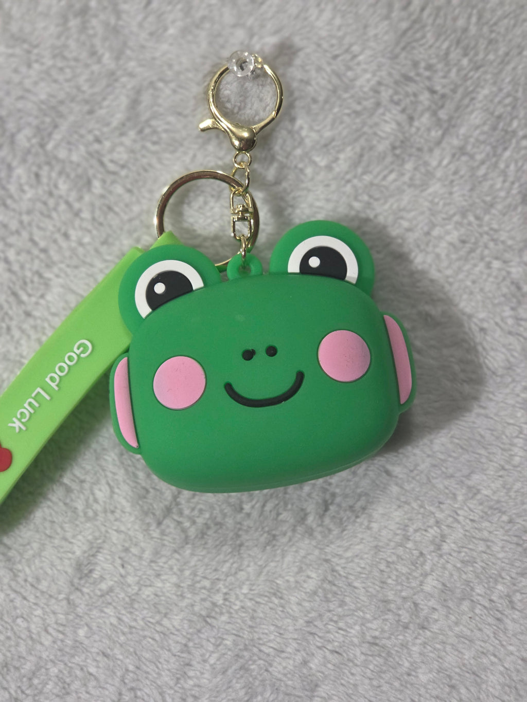 Kawaii green frog face silicone mini pouch keychain front view showing smiling frog face with pink cheeks and Good Luck wristlet strap