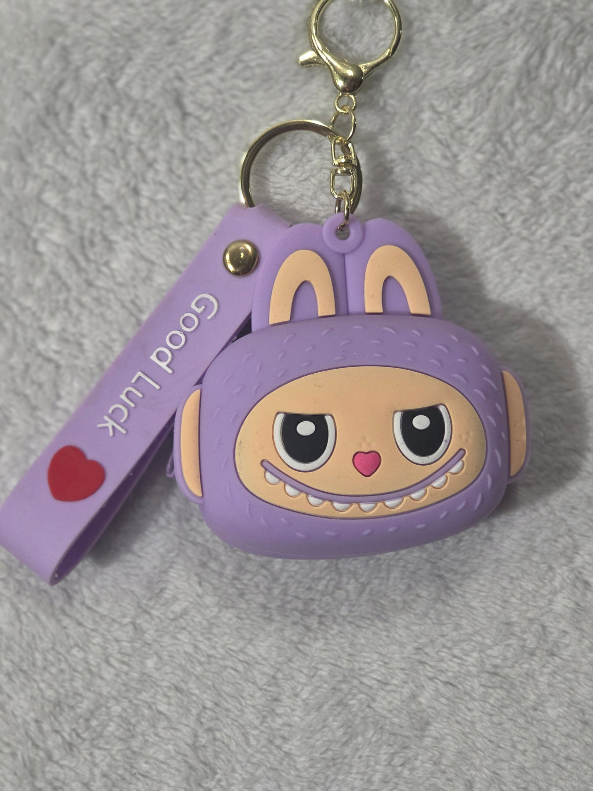 Labubu-inspired purple monster bunny mini pouch keychain front view showing character face with heart nose, toothy grin, and Good Luck wristlet strap