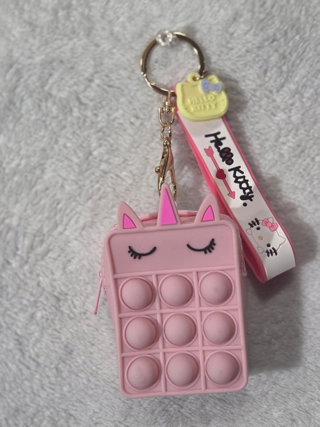 Hello Kitty pop-it pink silicone mini pouch keychain front view showing sleepy kitty face with hot pink ears and Hello Kitty print wristlet strap