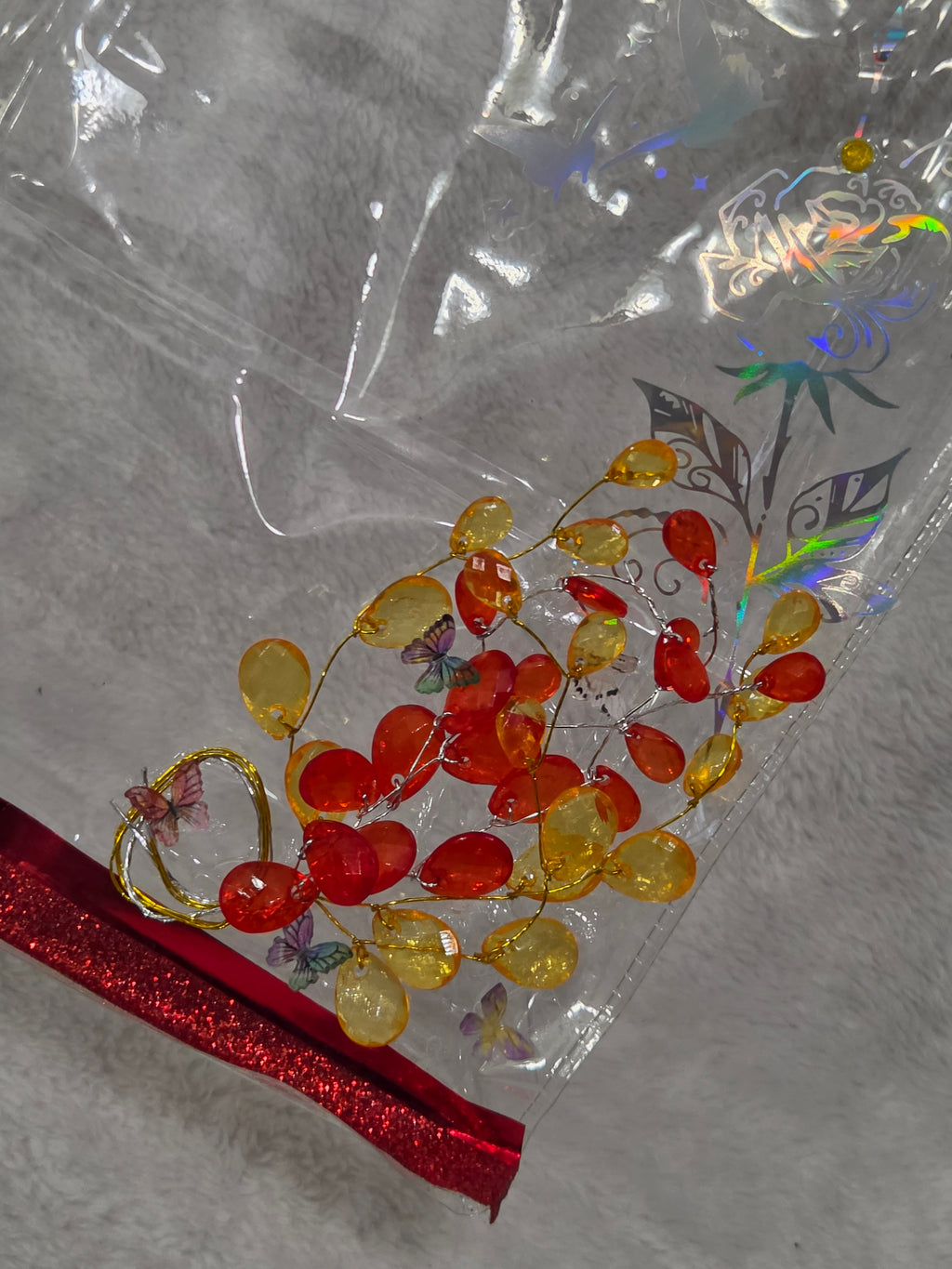 Close-up of hand-beaded red and amber cherry vine decoration on clear PVC bag