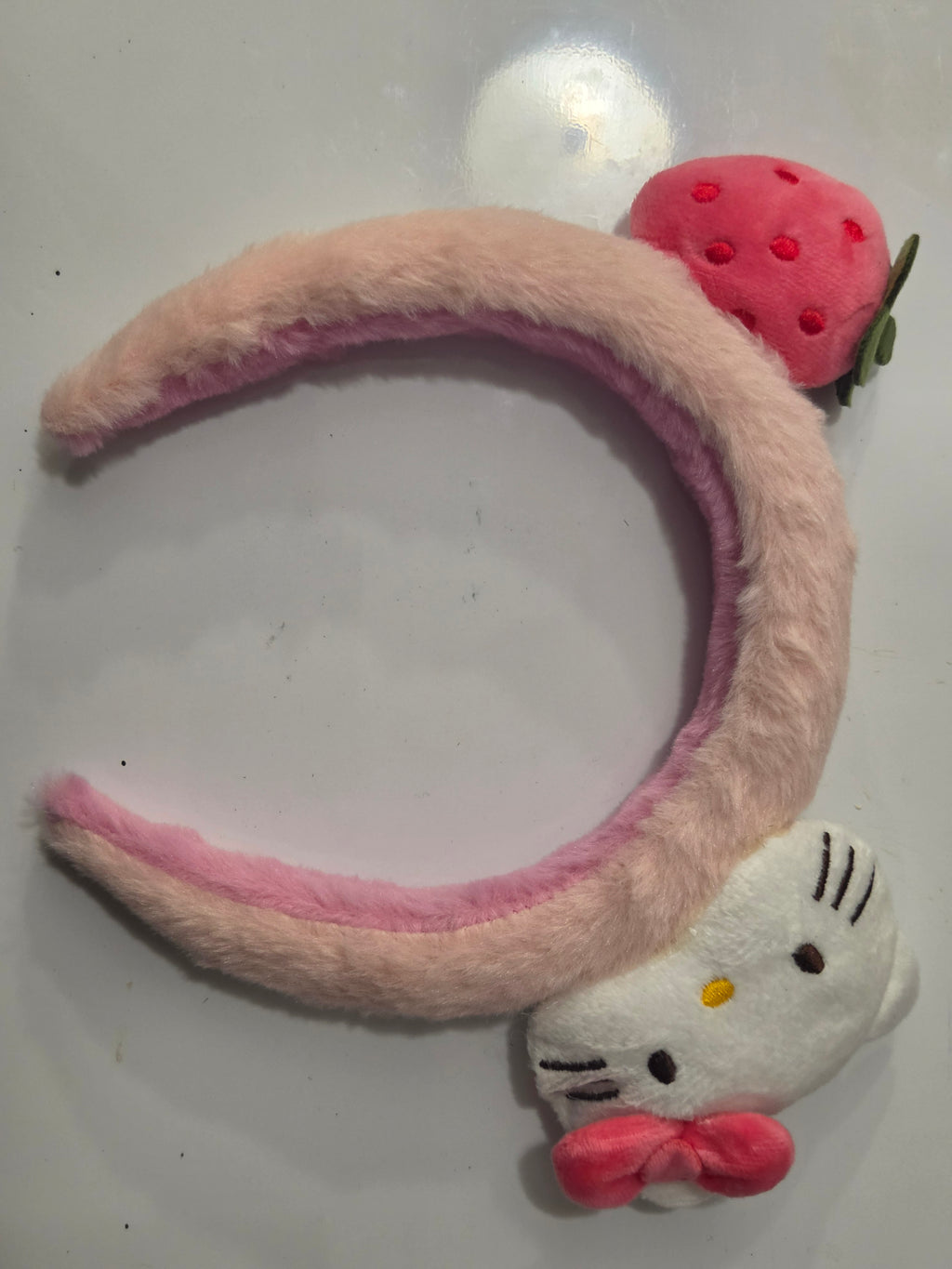 Pink plush headband with white cat-face, bow and strawberry decorations
