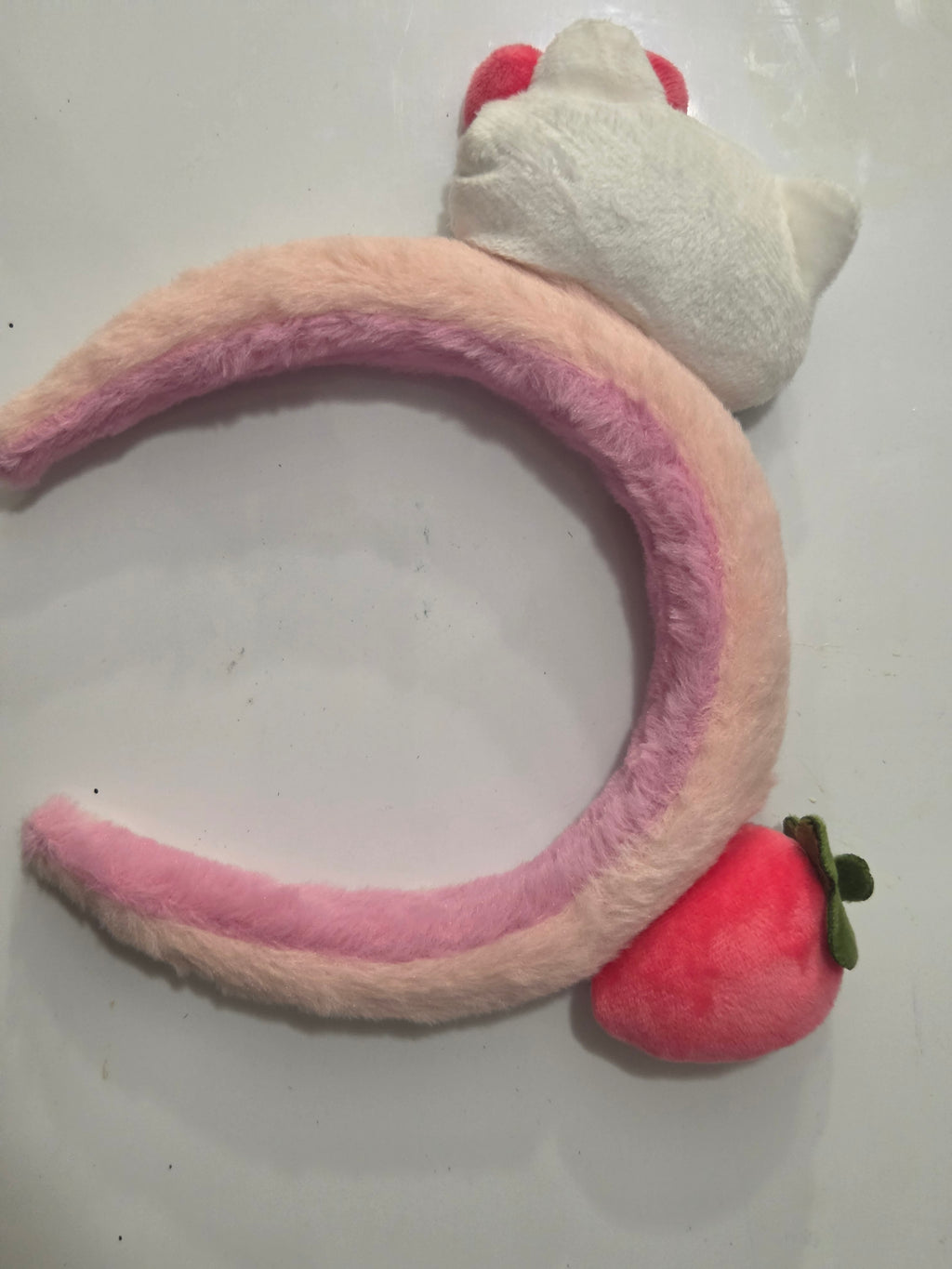 Reverse view of pink plush strawberry and cat headband